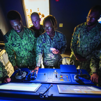 A group of military personnel viewing a dashboard