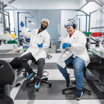A man and a woman sitting smiling in a lab environment