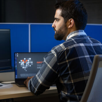 Man sits at a cubicle desk with a laptop